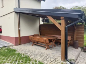Drewniany stół i ławki pod zadaszeniem – miejsce odpoczynku dla mieszkańców kwater